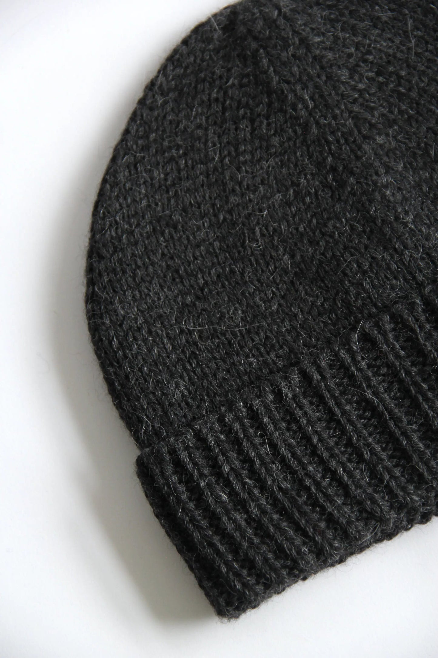 Close-up of a lead grey baby alpaca knitted beanie on a white background
