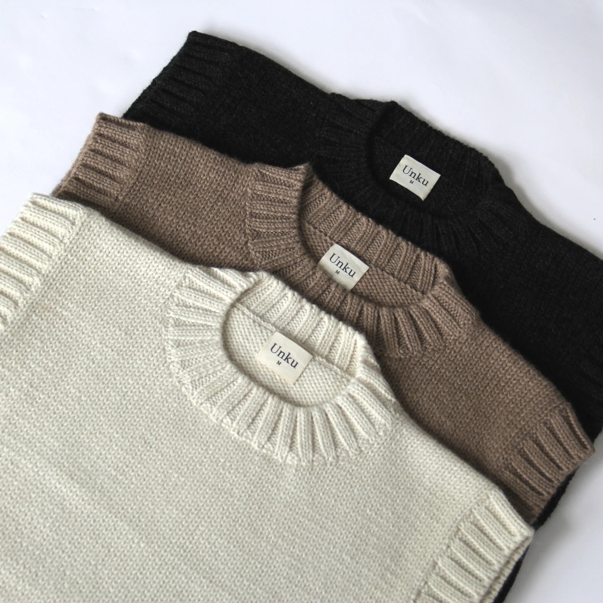 Three 100% Peruvian baby alpaca sweater vests in neutral tones on a white background
