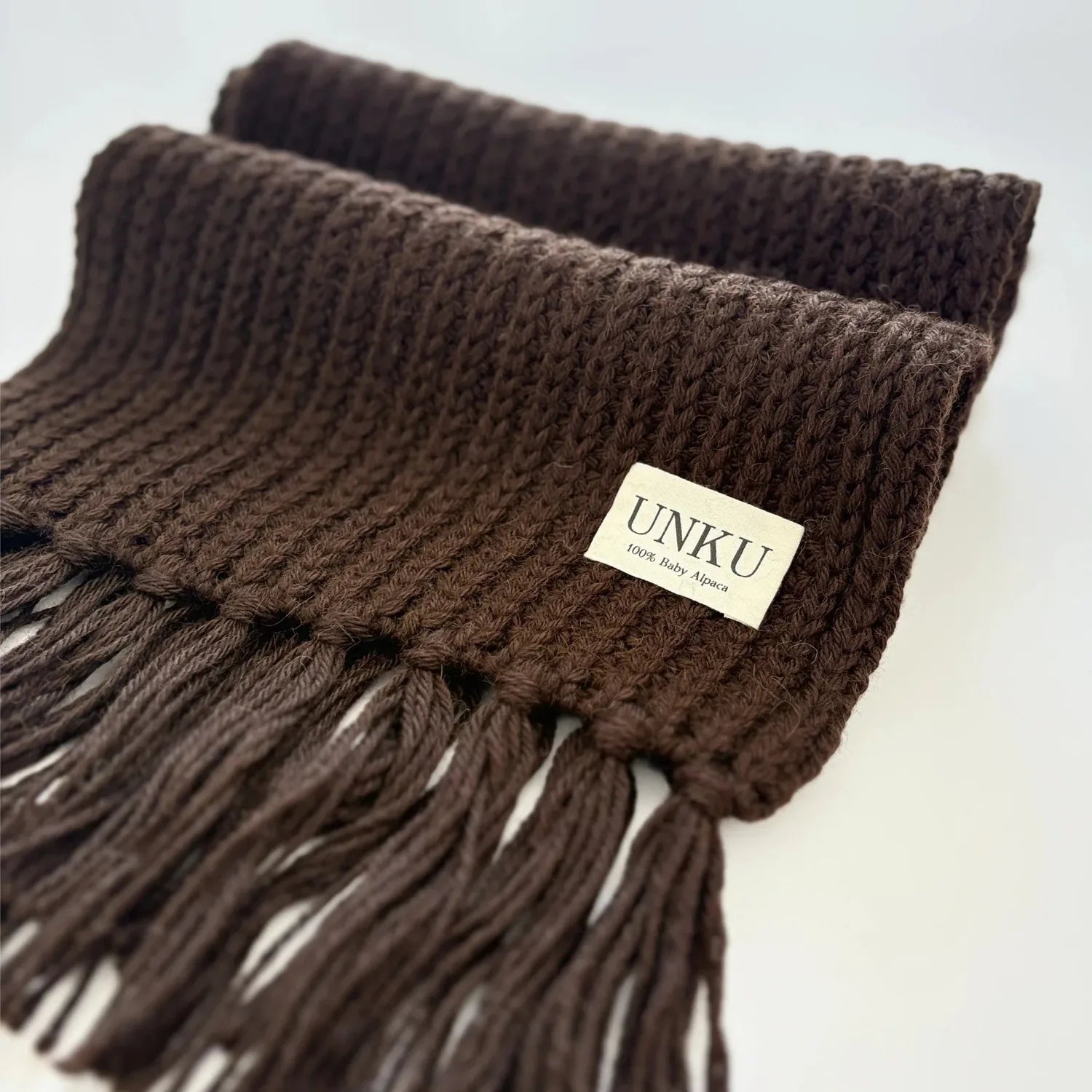 A brown 100% Peruvian baby alpaca scarf on a white background