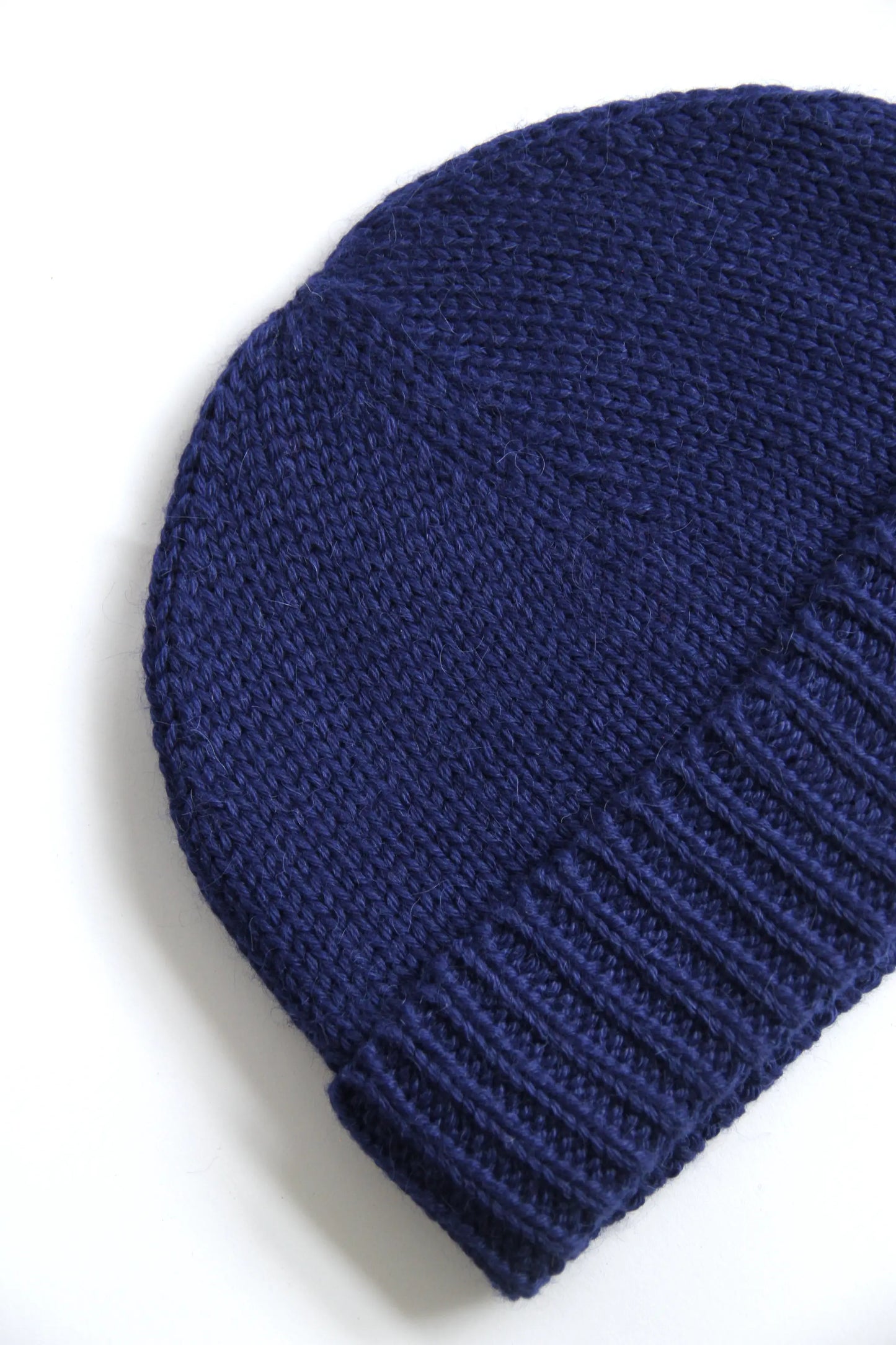 Close-up of a blue baby alpaca knitted beanie on a white background