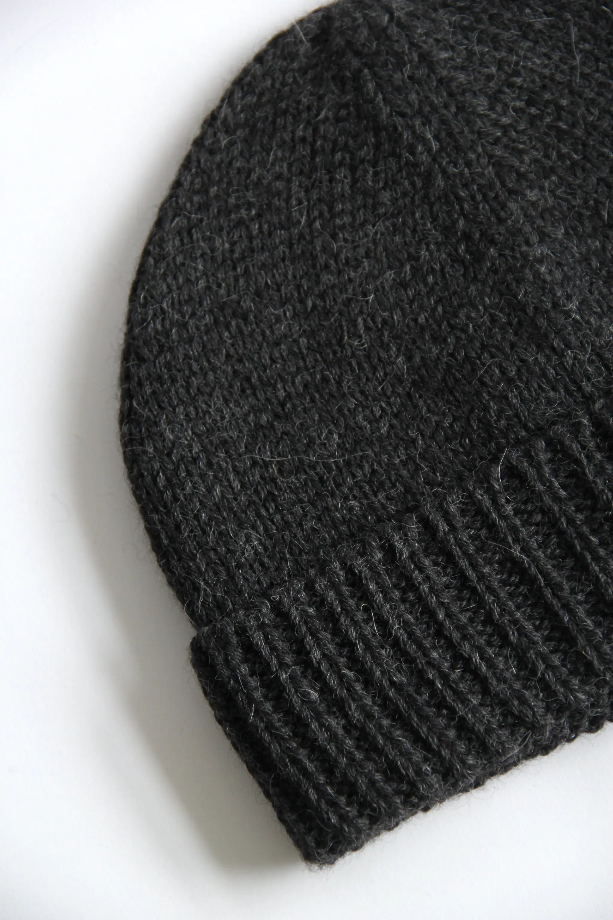 Close-up of a lead grey baby alpaca knitted beanie on a white background