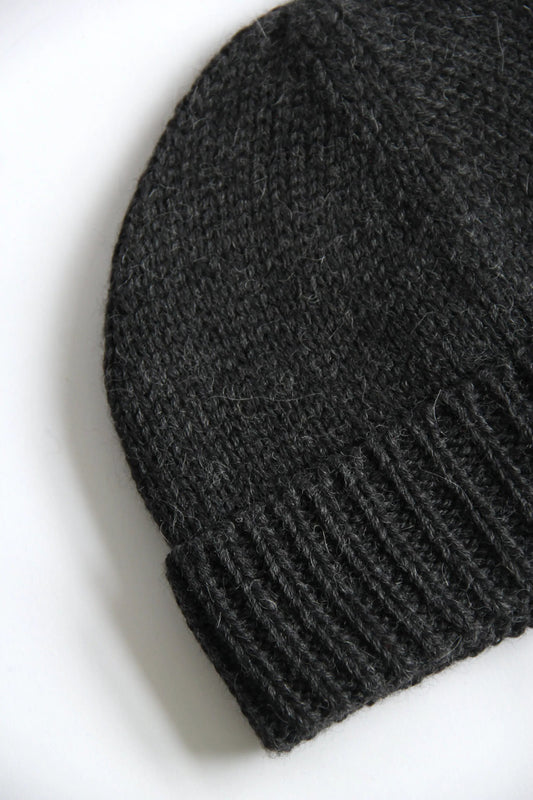 Close-up of a lead grey baby alpaca knitted beanie on a white background