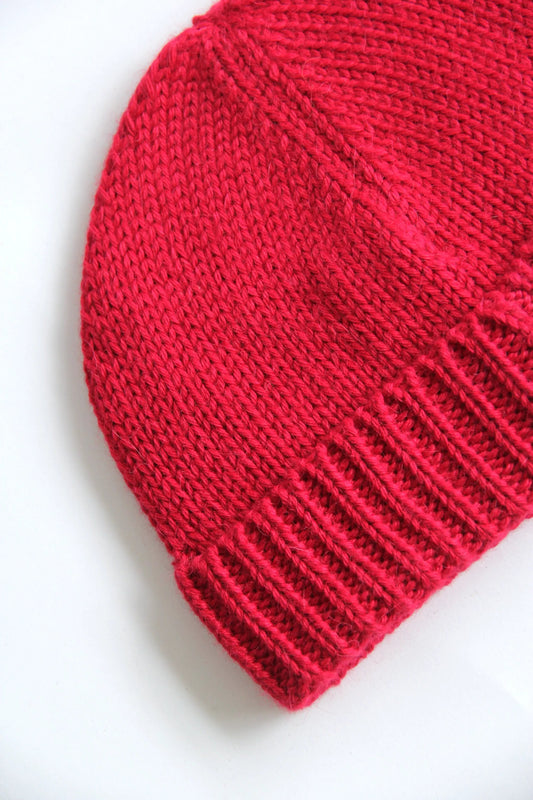 Close-up of a fuchsia baby alpaca knitted beanie on a white background