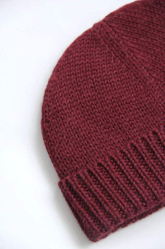 Close-up of a cherry red baby alpaca knitted beanie on a white background