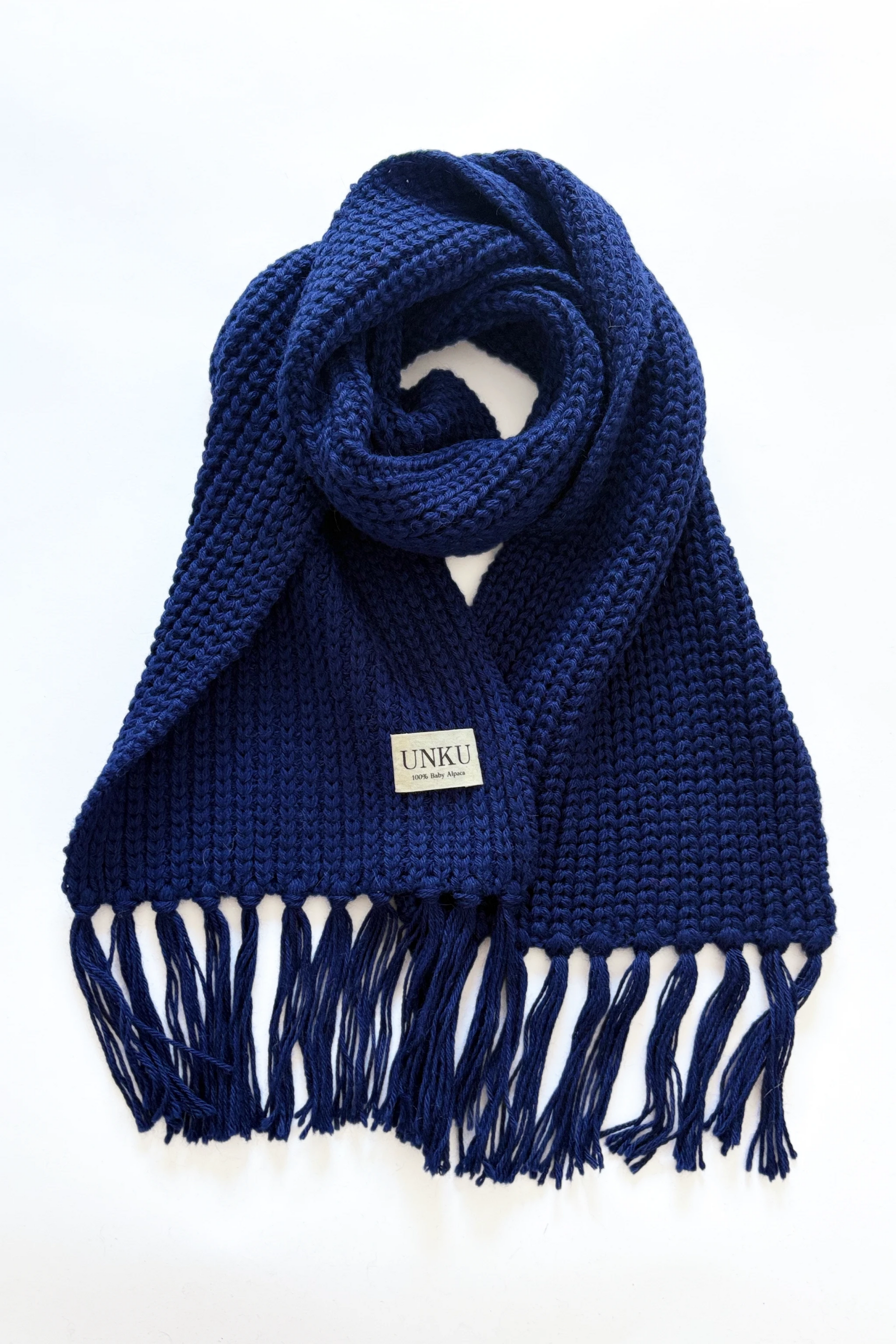 A sapphire blue baby alpaca knitted scarf on a plain white background