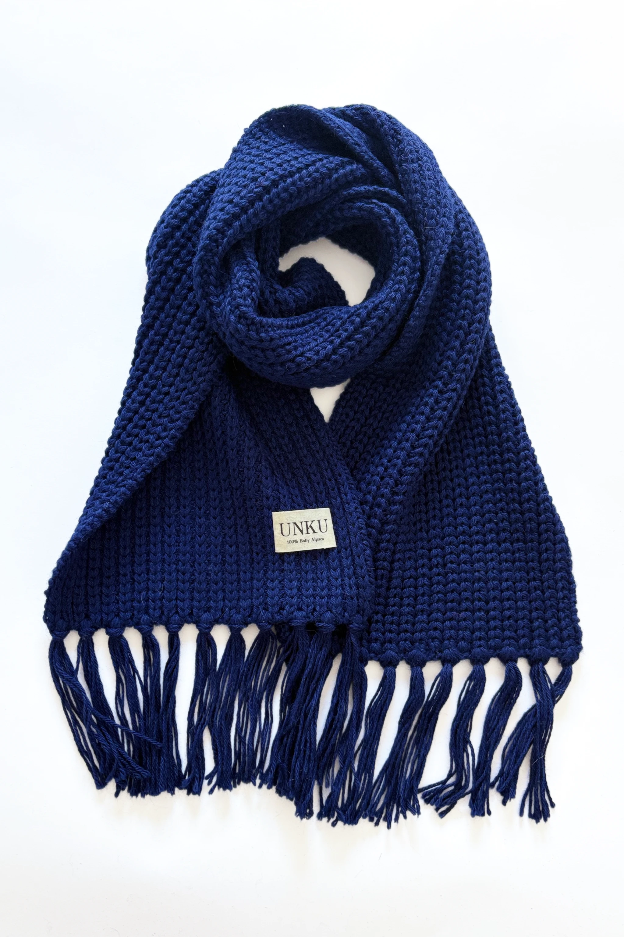 A sapphire blue baby alpaca knitted scarf on a plain white background